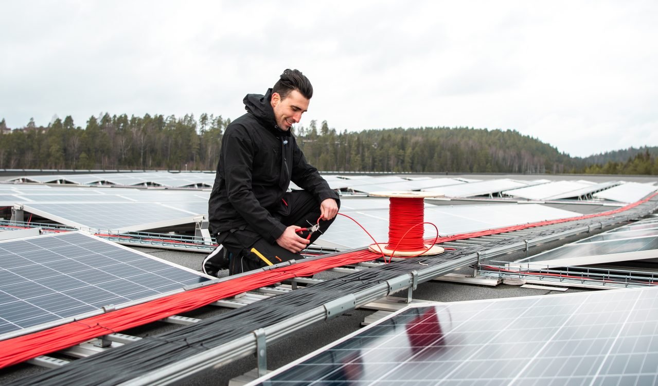 elektriker på taket av et næringsbygg som jobber med solceller